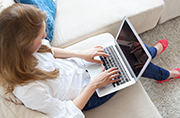 Image of person sat at home with laptop open on lap.