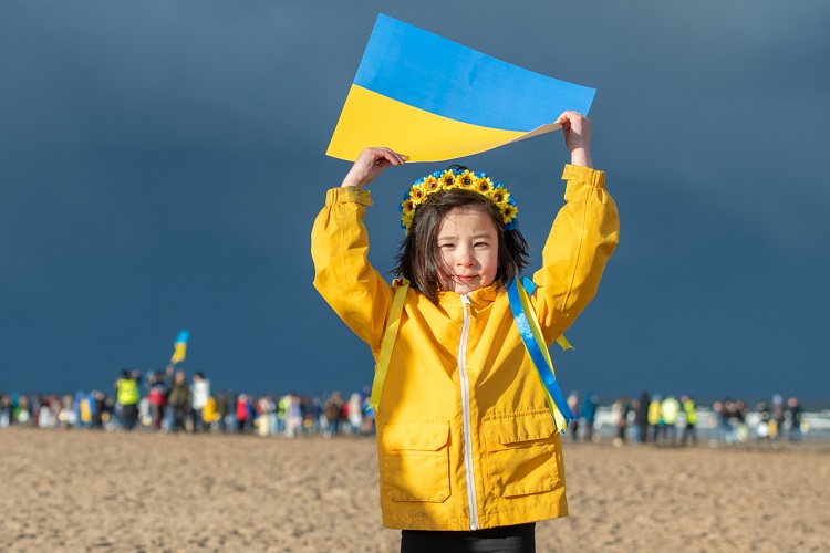 Child holding Ukrainian flag on West Sands beach at peace rally