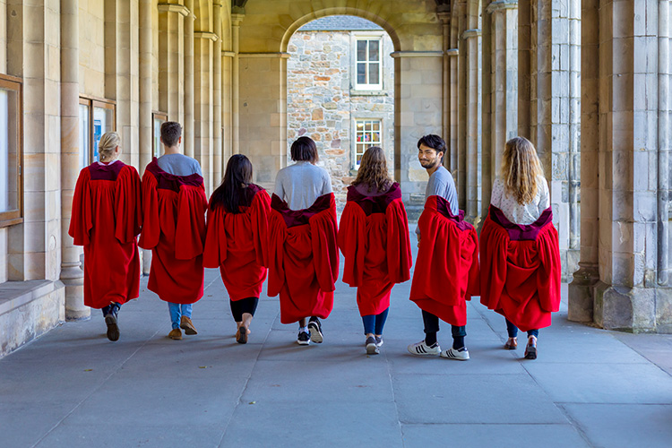 group of students in red gowns, one turning around