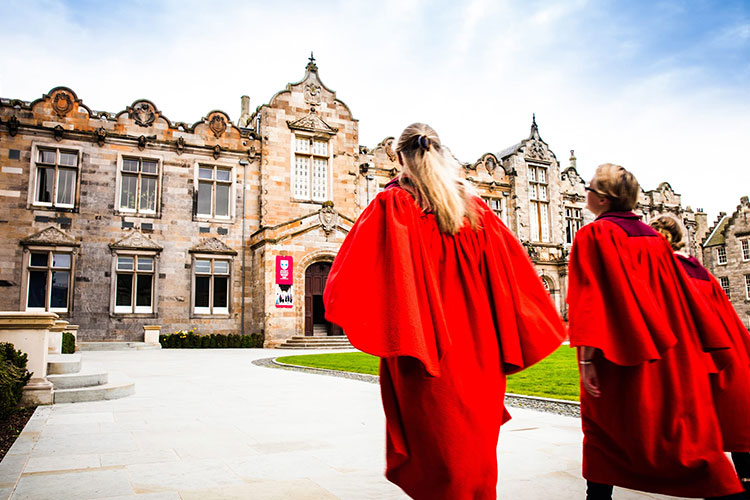 Students in gowns walking through the quad