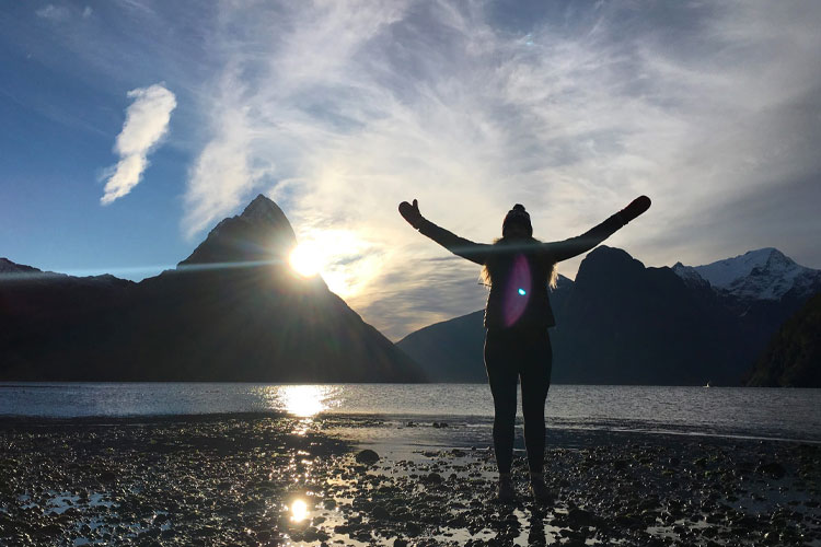 Person with arms out overlooking mountains and a lake