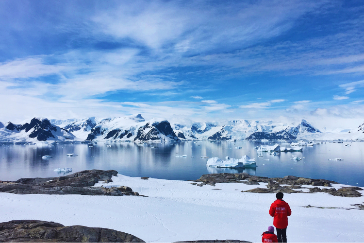 Picture of researcher looking out over bay and mountains covered in snow