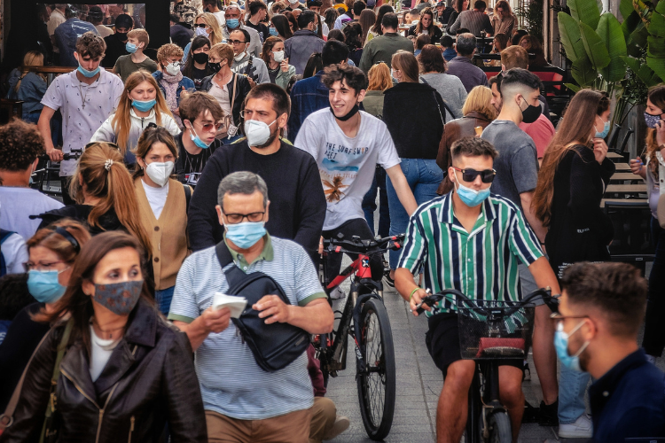 Photograph of a crowd of people wearing protective masks in a busy shopping street