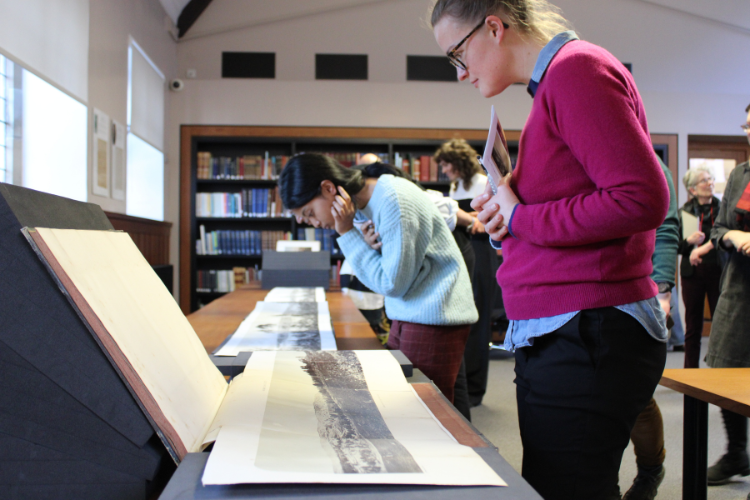 Two people looking at archival material laid out on a table in Reading Room