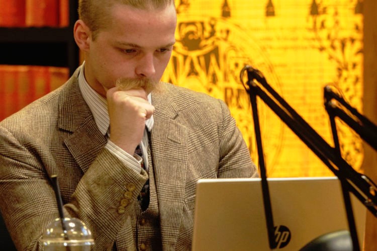 Member of staff reading on a laptop in a University library