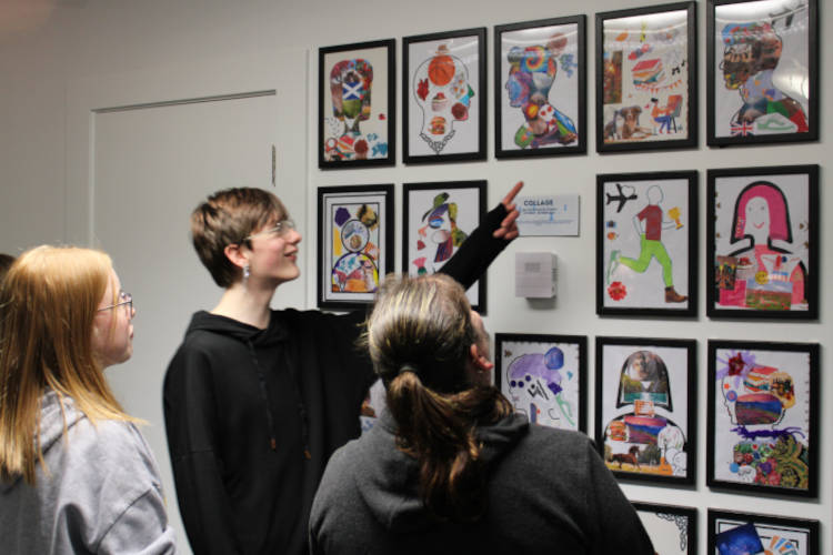 Students looking at framed art collages on a wall