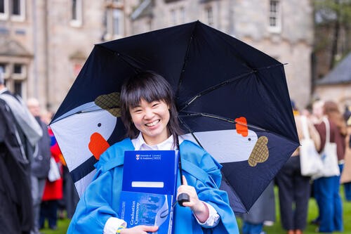 student holding ubmrella at graduate event