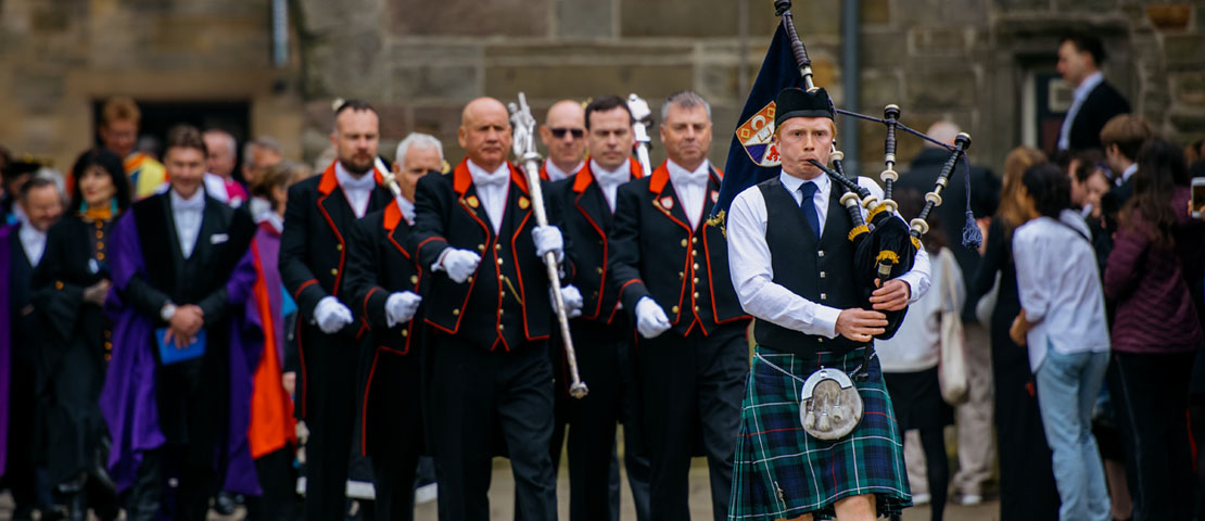 The graduation procession being led by a piper