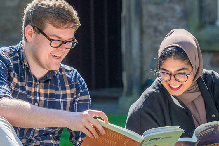 Two students reading a book and smiling