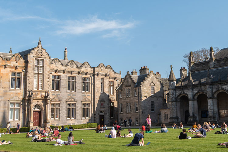 St Andrews students sit on the grass at St Salvator's Quad in the sunshine
