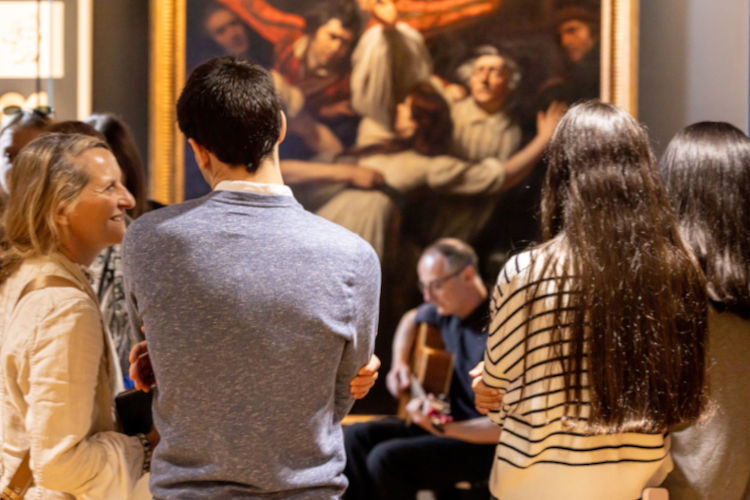 Group of people attending an exhibition with live music at the Wardlaw Museum