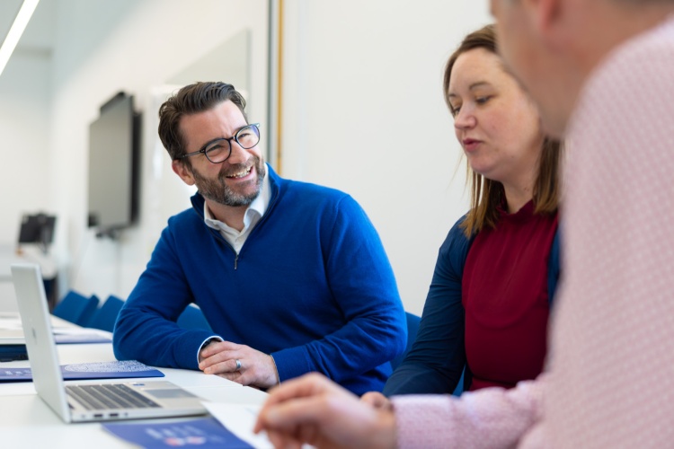 Male and female students working at a shared laptop computer.