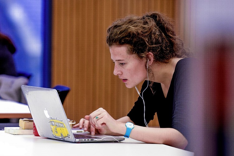 Female student works at a laptop on a desk