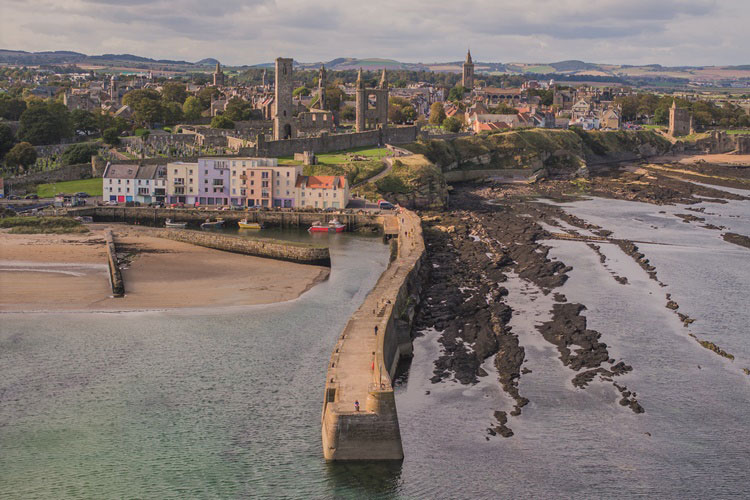 A scenic photo of St Andrews harbour, with the town in the background.
