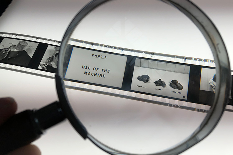 A filmstrip being examined through a magnifying glass. The first frame reads 