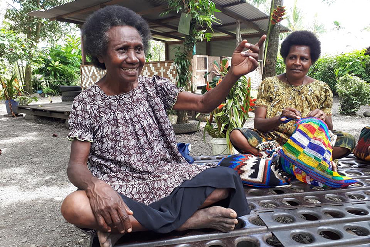 Women Papua New Guinea sitting and working on embroidery
