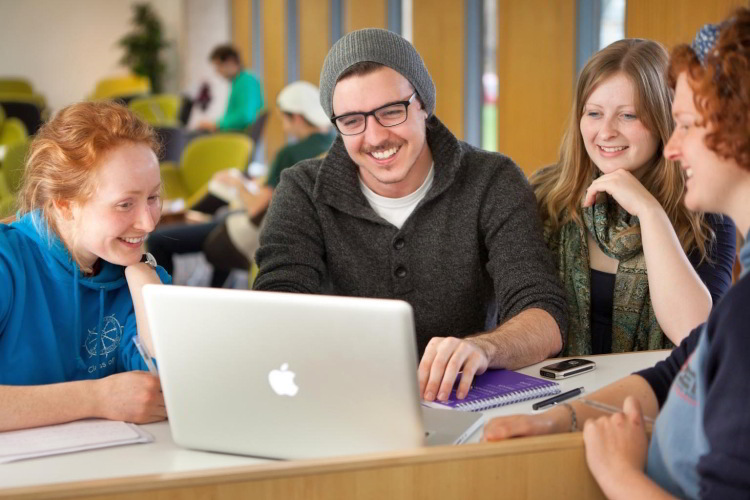 Photo of students sitting around a laptop