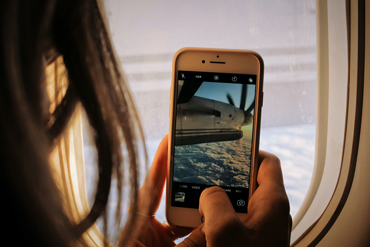 a woman on a plane is taking a picture out the window on her phone