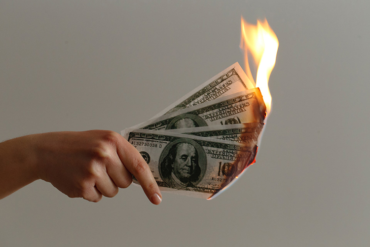 hand holding US 100 dollar bills which are on fire