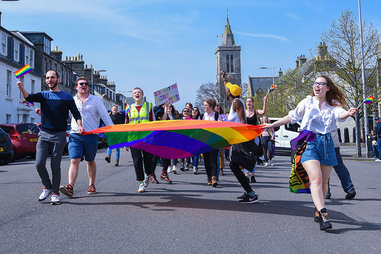 students marching on North Street with rainbow flags and placard saying I'M GAY FOR CLIMATE JUSTICE