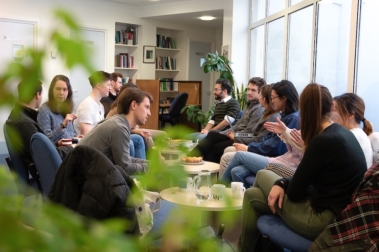 Students conversing round coffee tables