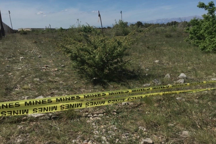 A field fenced in with a tape warning of mines.