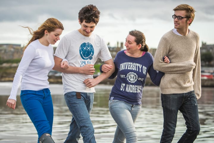Students linking arms across the beach