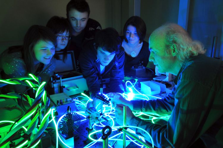 Students with professor wroking on optics experiment