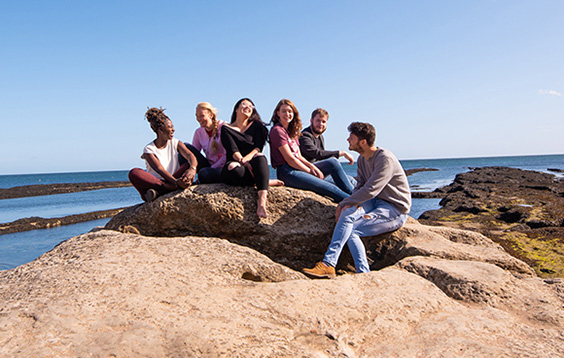 Students on a rock at the beach