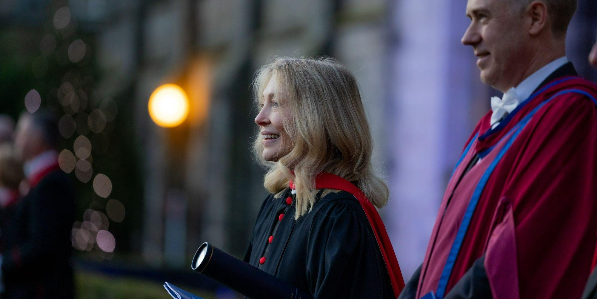 Kirsty Young, pictured in graduation robe, and holding a graduation scroll