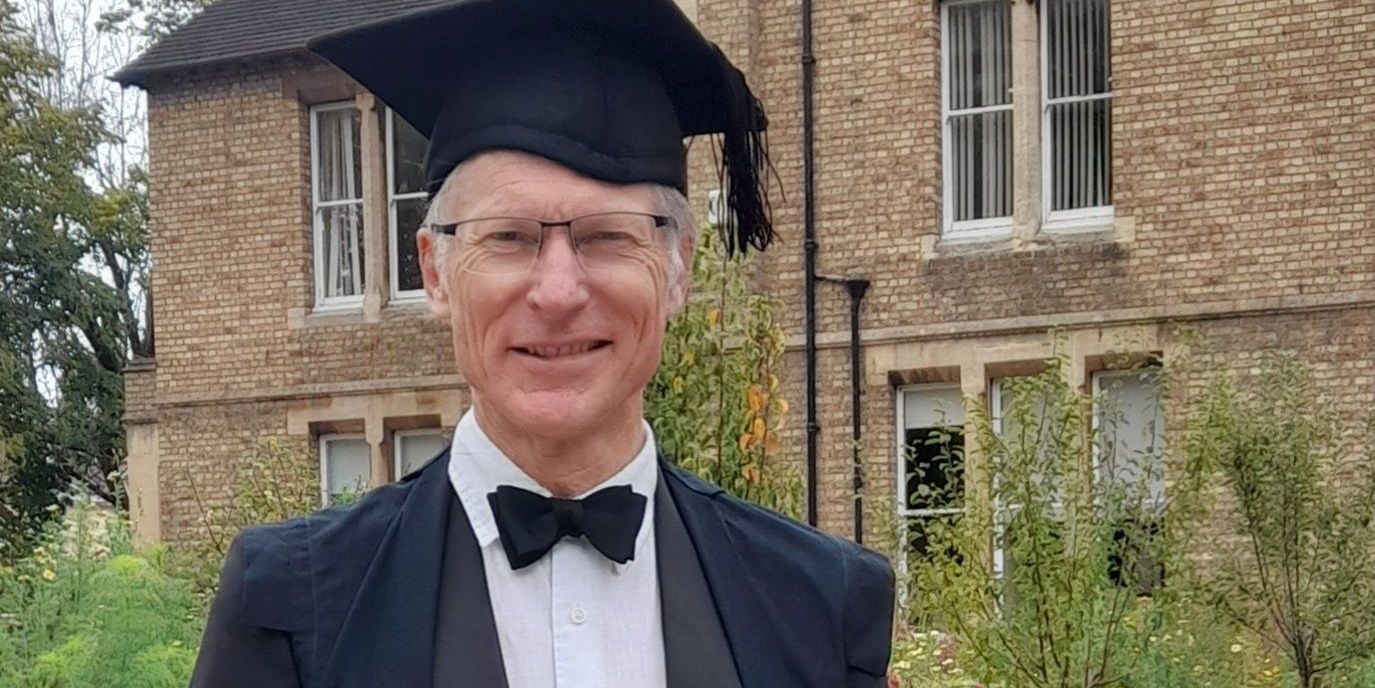 Robert Bullard smiles at the camera, he is wearing an academic cap and a suit with bow tie. 
