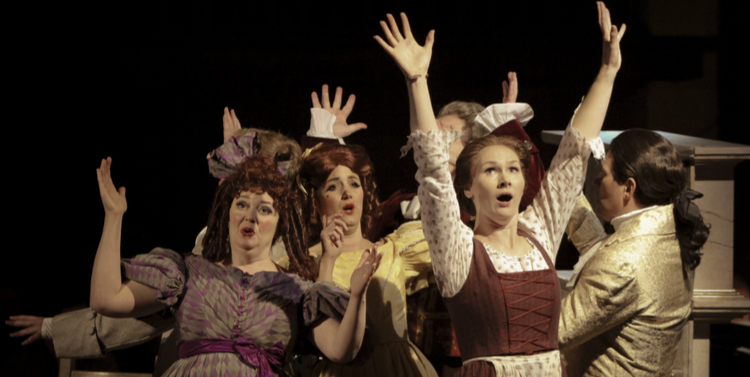 Diva Opera performers in period costume on stage. The performers can be seen to be singing and raising their arms. Diva Opera performers in period costume on stage. The performers can be seen to be singing and raising their arms.