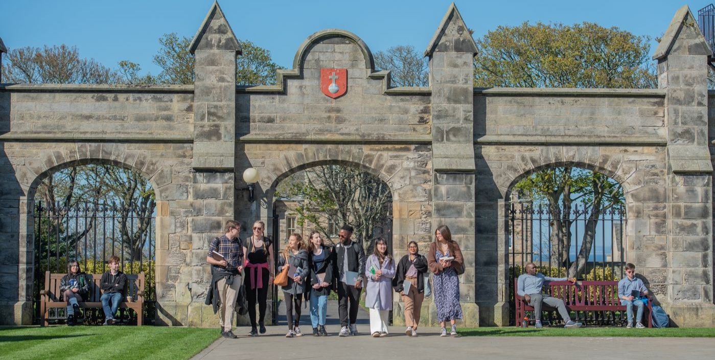 A group of eight students walk side by side smiling into St Salvator's Quad A group of eight students walk side by side smiling into St Salvator's Quad