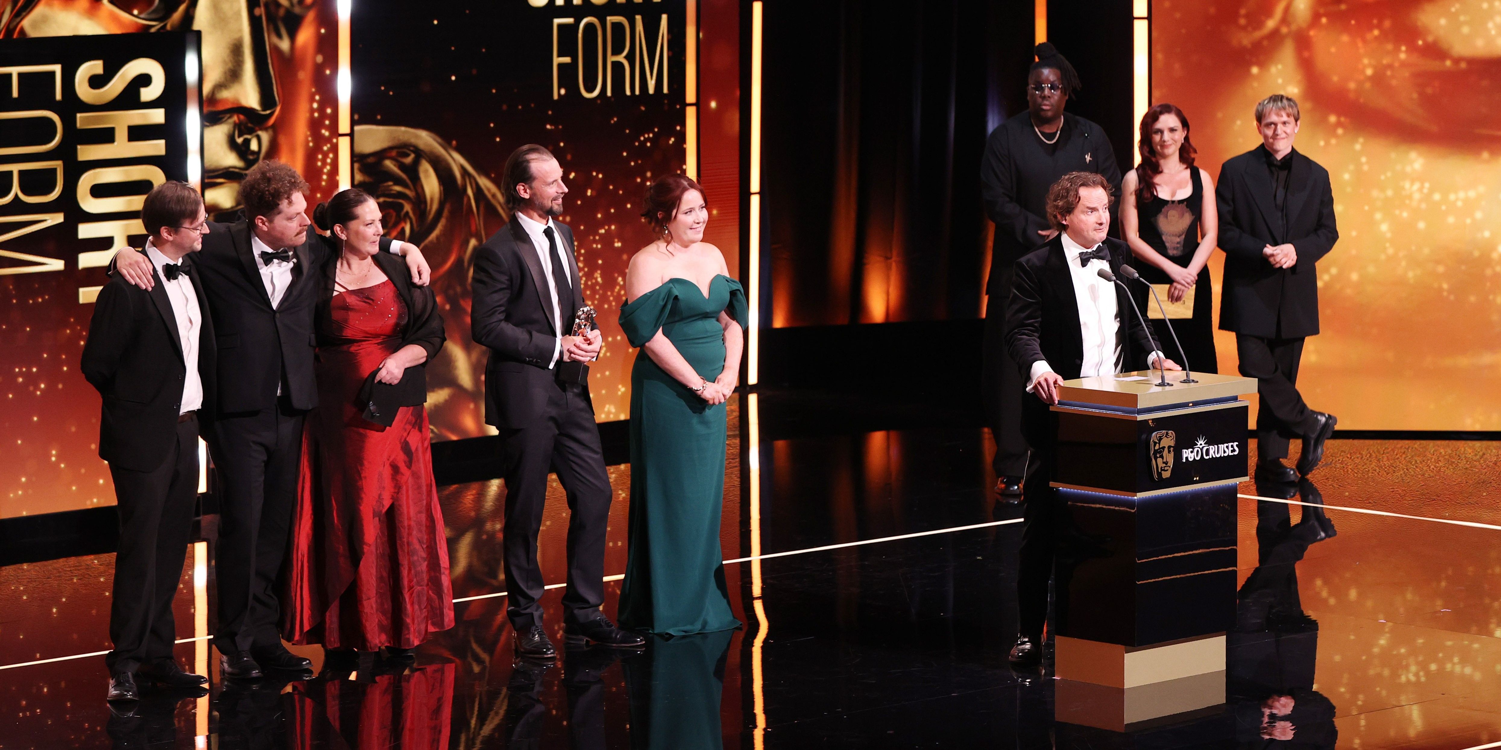 Jonny stands on stage at the 2026 BAFTAs, behind him are the JustSo team Jonny stands on stage at the 2026 BAFTAs, behind him are the JustSo team
