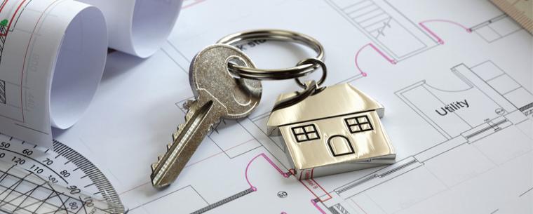 A key with a house keyring laid on top of floorplans.