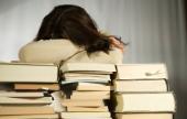 Student resting head on books