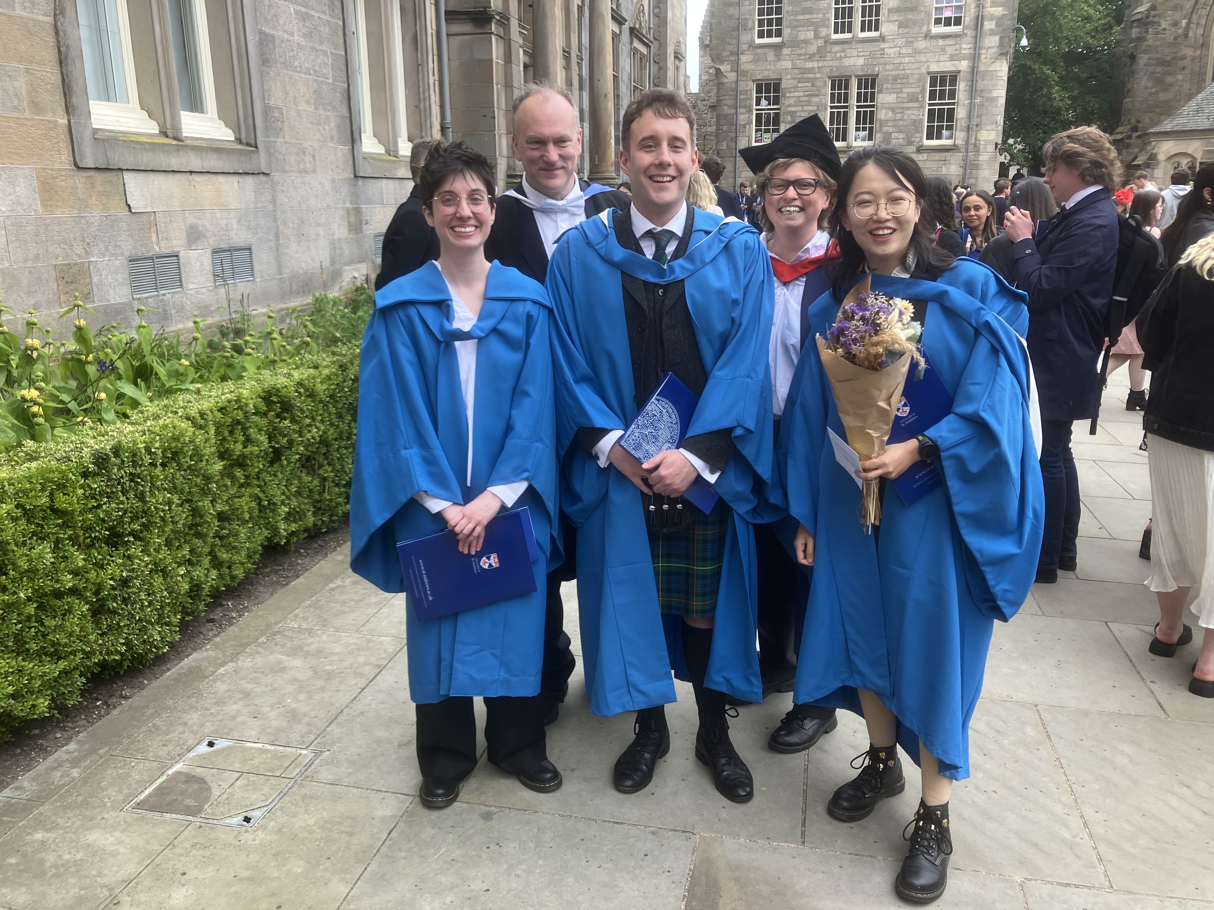 Five gowned people at graduation.